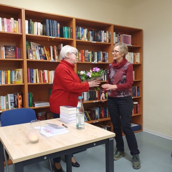 Gisela Stölzer überreicht im Namen der Bücherbörse und der Gäste als Dankeschön einen Blumenstrauß
